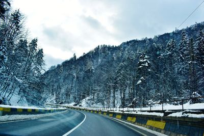 Road amidst snowcapped mountains against sky