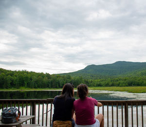 Rear view of people looking at mountains against sky