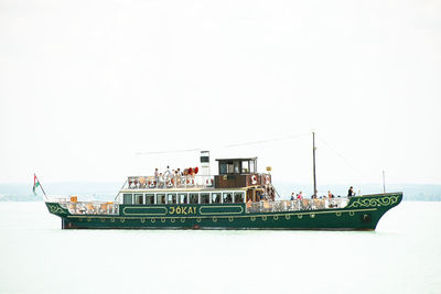 People on boat in sea against clear sky