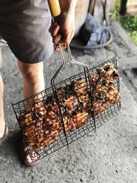 Midsection of man preparing food on barbecue grill