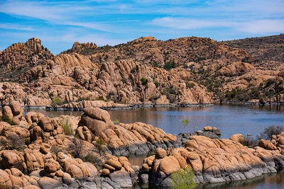 Scenic view of rocks by lake against sky