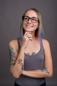 Portrait of smiling young woman standing against wall