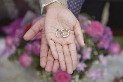 Close-up of hands holding purple flower