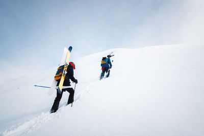 Side view of a group of people climbers skiers climbing up the snowy slope. snow-capped mountains