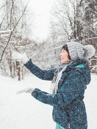 Smiling woman is playing with snow. fun in snowy winter forest. woman laughs