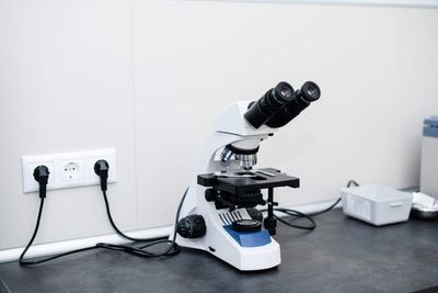 Close-up of coin-operated binoculars on table against white wall