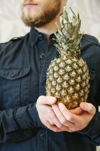 Midsection of man holding pineapple