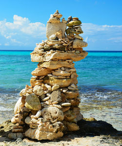 Tall tower of sea stones on the sand at the water's edge