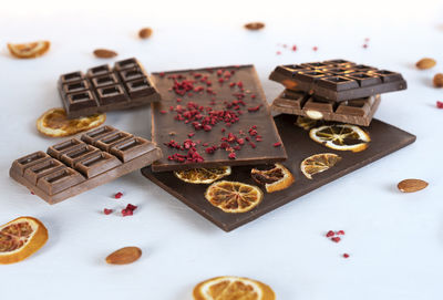 Homemade milk and bitter chocolate bars with sublimated berries, orange slices and nuts.