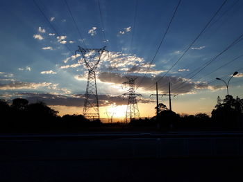 Silhouette electricity pylon against sky during sunset