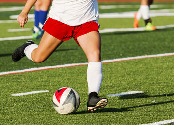 Low section of people playing soccer on field