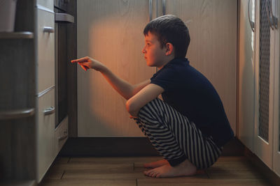 Side view of young woman sitting on hardwood floor at home