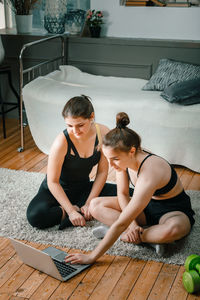 High angle view of friends sitting on wooden floor