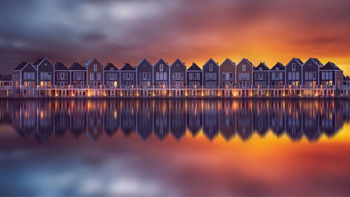 Reflection of house in canal against sky during sunset