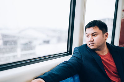 Portrait of young man looking through window