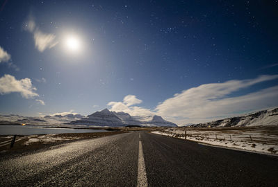 Empty road amidst landscape against sky