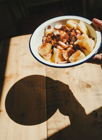 High angle view of a dish of octopus with potatoes casting shadow on table