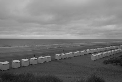 Scenic view of beach huts at sea against sky