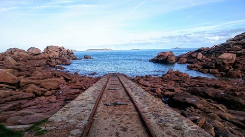 Railroad tracks by sea against sky