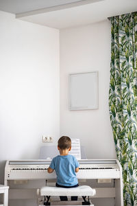 Rear view of boy sitting on table against wall