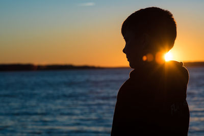 Silhouette man standing by sea against sky during sunset