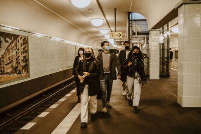 Young friends walking at subway station during pandemic