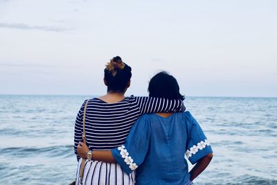 Rear view of female friends standing at beach