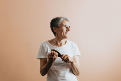 Portrait of young woman standing against gray background