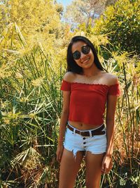 Portrait of beautiful woman in sunglasses standing amidst plants
