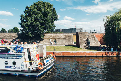 Boats in swimming pool by river against sky