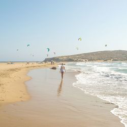 Rear view of woman walking at beach against clear sky