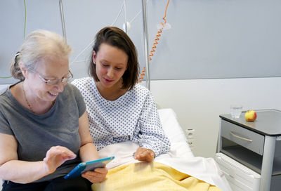 Grandmother and granddaughter using digital tablet in hospital ward