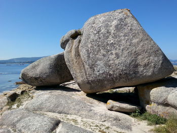 Close-up of rocks on beach against clear blue sky