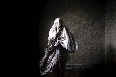 Close-up of woman hanging on rope against wall