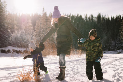 Mother and children walking on a snowy field on a sunny day