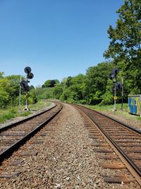 Rear view of railroad tracks amidst plants against sky