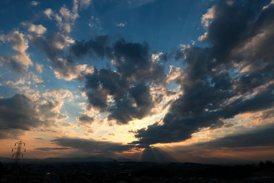 Scenic view of landscape against cloudy sky at sunset