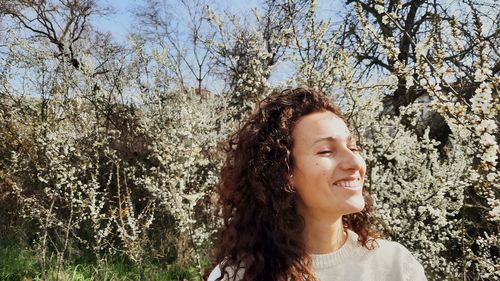 Portrait of young woman standing against trees