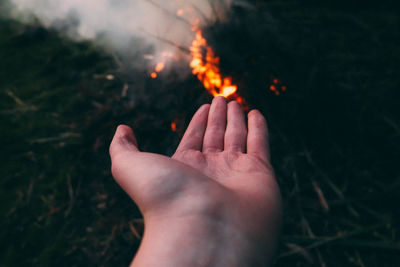 Cropped hand of woman against bonfire
