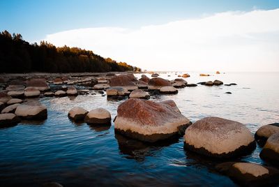 Rocks on beach against sky during sunset