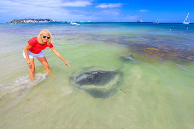 Portrait of woman pointing at stingray in sea