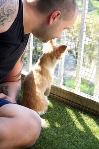 Man looking at cat on field