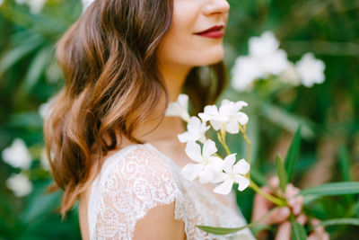 Close-up of woman against white flowering plants