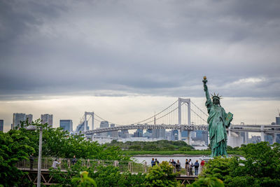View of bridge in city against cloudy sky