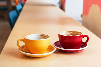 Two cups of coffee on wooden table in cafe.