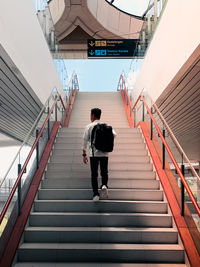 Rear view of man walking on staircase