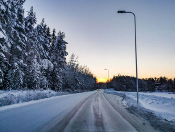 Road amidst snow covered trees against sky