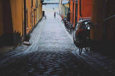 Narrow street with cobblestones where a lot of bicycles is parked on the side 