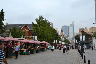 People walking on street amidst buildings in city