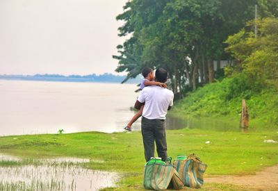 Rear view of friends walking with dog on water